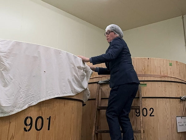 The toji lifts the cover from a cedar fermentation tank at Ninki Shuzo, Nihonmatsu, Fukushima